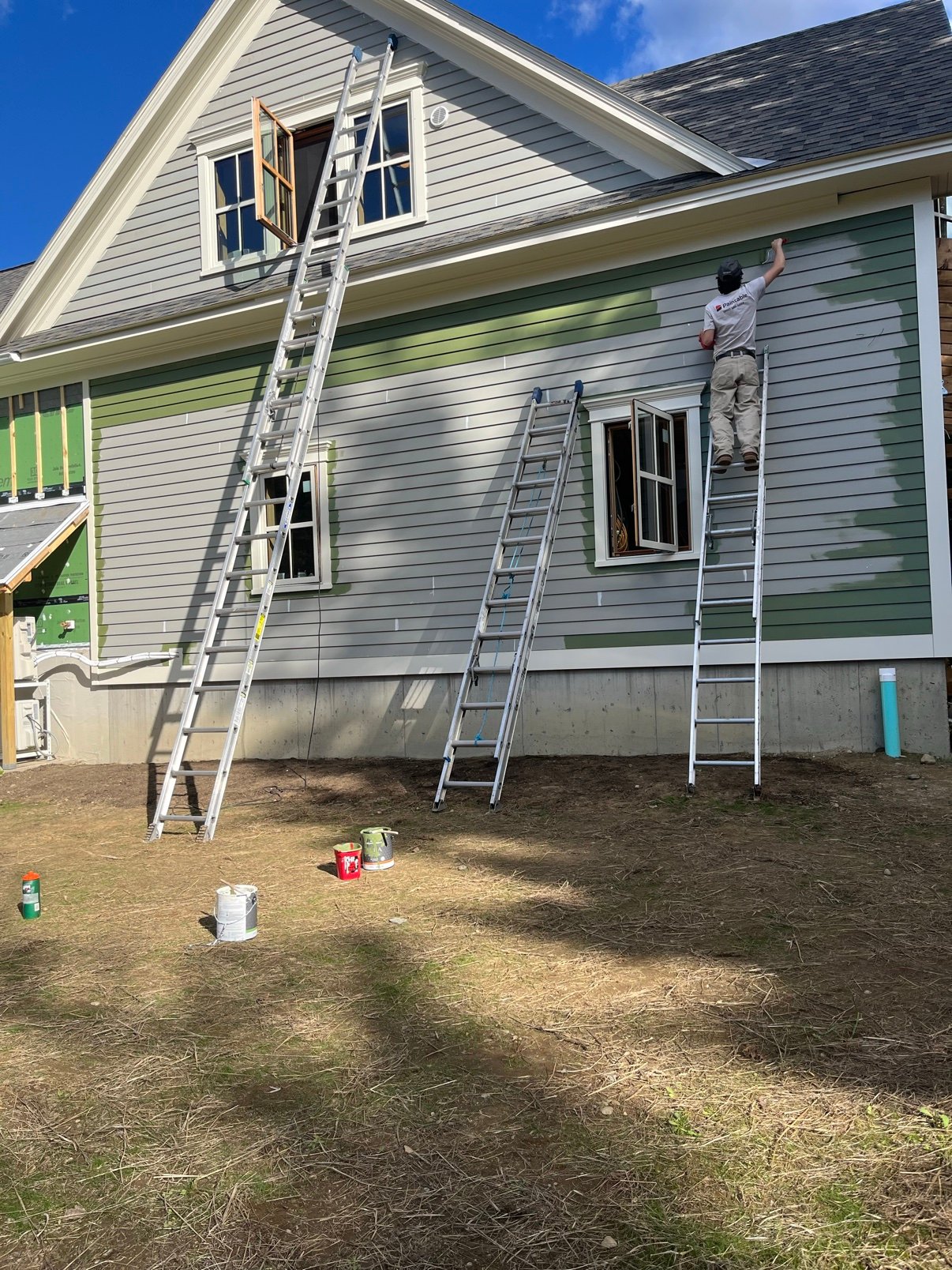 Paintable crew painting a Vermont home exterior from a ladder